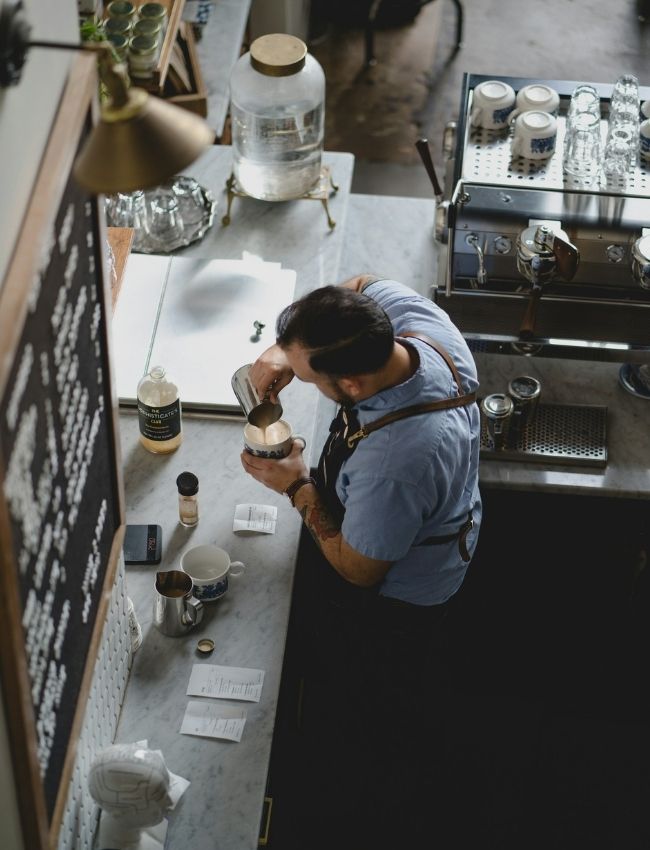 Barista bereitet Kaffee in einer modernen Café-Küche zu, Fokus auf Detail und Qualität